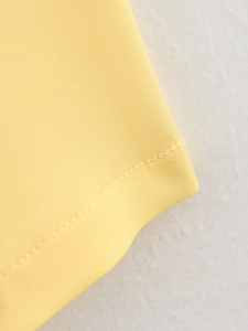 Close-up of fine stitching and woven fabric texture on bright yellow waist summer outfit