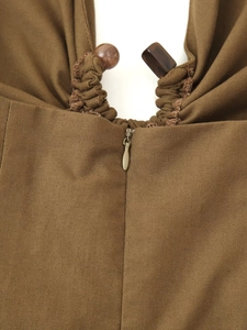 Détail de robe tissée marron olive avec fermeture éclair invisible et perles en bois