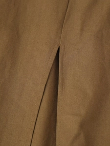 Détail du tissu texturé marron montrant la fente de l'ourlet et la finition de couture