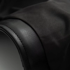 Close-up of black faux leather texture with litchi grain and fine stitching on jacket