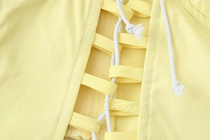 Close-up of yellow backless top showing the white lace-up straps and detailed stitching