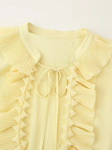 Detail of ruffled pleats and drawstring tie on a light yellow summer blouse