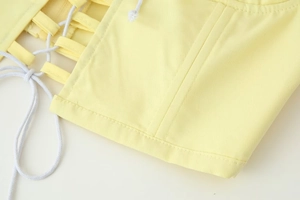 Detail of light yellow structured top featuring lace-up cords and premium double stitching