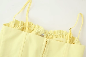 Detail of adjustable straps, ruffled neckline, and back zipper on yellow crop top