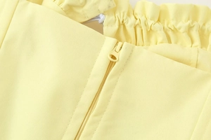 Detail of light yellow cropped top showing textured twill fabric and matching resin zipper