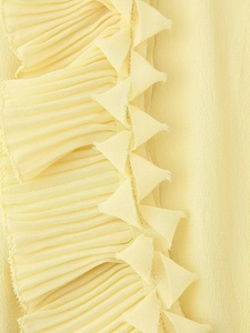 Macro detail of pale yellow pleated chiffon fabric with unique zigzag serrated lace edges