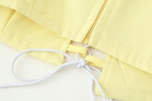 Macro shot of yellow twill fabric hem with metal zipper and white cotton drawstring