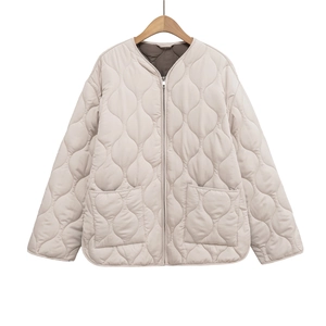 Dettaglio della giacca trapuntata beige chiaro con cuciture curve e zip in metallo