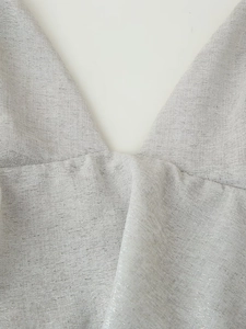 Détail d'une robe argentée à col en V montrant le tissu texturé et les plis