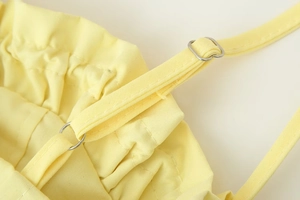 Detail of light yellow summer top showing adjustable thin straps and ruffled elastic edge