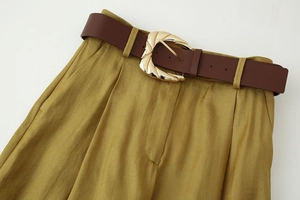Dettaglio dei pantaloni a vita alta senape con cintura marrone e fibbia dorata fine