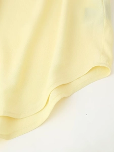 Detail shot of light yellow shirt showing the curved hem and precise double-needle stitching