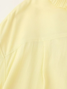 Detail of light yellow summer blouse showing double stitching and pleated neckline texture