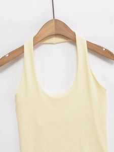Detail of light yellow ribbed knit halter top featuring a U-neckline on a wooden hanger