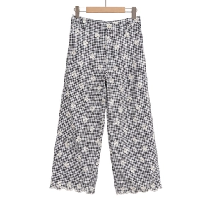 Détail du pantalon vichy taille haute avec broderie marguerite blanche et bord festonné