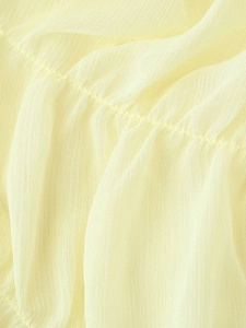 Detailed macro view of light yellow pleated chiffon fabric texture and refined stitching
