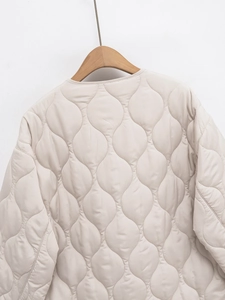 Dettaglio del retro di una giacca trapuntata beige con cuciture a cipolla e scollo rotondo