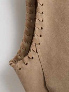 Macro shot of khaki suede vest showing intricate leather cord woven edge and texture