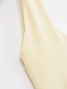 Close-up of the light yellow ribbed knit fabric texture and premium shoulder stitching