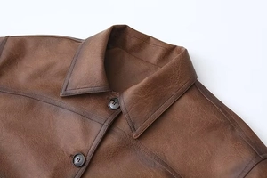 Dettaglio della giacca in pelle PU marrone vintage con revers e bottoni opachi