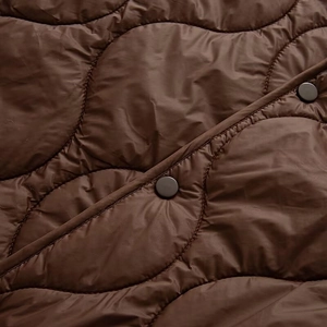Close-up of dark brown quilted jacket with onion-pattern stitching and metal snap buttons