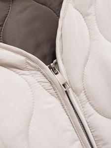 Dettaglio della zip in metallo argento e trama trapuntata su giacca beige