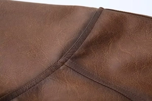 Dettaglio macro della giacca in pelle marrone vintage con cuciture doppie rifinite