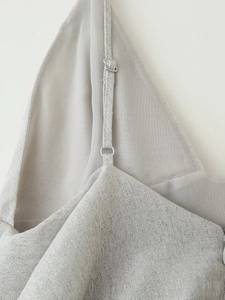 Détail de la boucle métallique réglable et du tissu pailleté sur la robe argentée