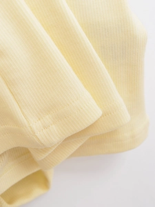 Detail of light yellow ribbed fabric texture with double-needle stitching on edges
