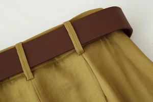 Vista macro dei pantaloni oro oliva con cintura marrone scuro e trama del tessuto fine