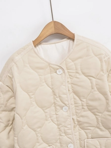 Detail of onion quilted stitching and round button closure on beige lightweight jacket
