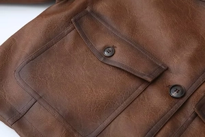 Dettaglio della giacca vintage in pelle PU marrone con tasca a patta e trama premium