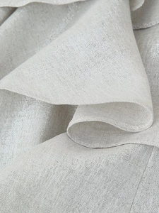 Macro view of layered ruffles and fine hem on silver metallic woven dress fabric