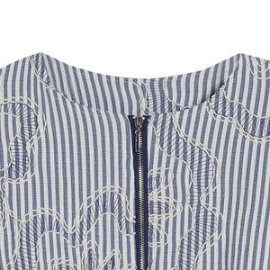Close-up of crew neck textured bomber jacket with blue stripes and wavy embroidery details
