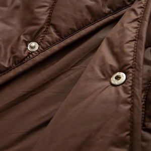 Close-up of diamond quilted brown nylon jacket featuring shiny silver metal snap buttons
