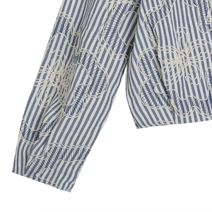 Detail of blue and white striped fabric with intricate white floral embroidery on a jacket