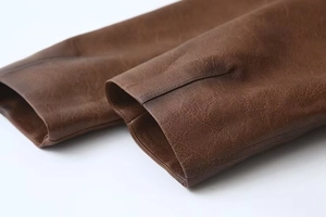 Dettaglio del polsino della giacca in pelle PU marrone scuro vintage con cuciture fini