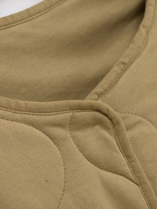 Détail du matelassage en losanges et des liserés sur une veste en coton de couleur kaki