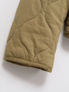 Détail du poignet matelassé oignon vert olive avec coutures soignées sur veste coton