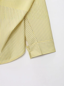 Close-up of a women's yellow striped shirt with pleated texture and cuff details
