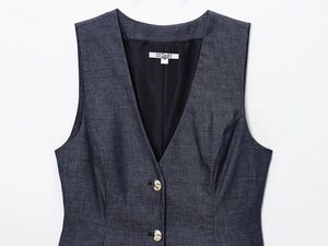 Close-up of dark blue denim vest with V-neckline, metal buttons and white woven neck label