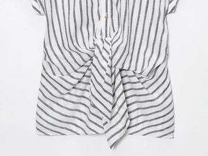 Dettaglio camicia a righe blu e bianche con un elegante nodo frontale sull'orlo