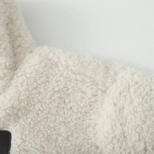 Detail of cream sherpa fleece texture with premium black leather trim accents