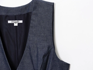 Detailed close-up of dark denim vest with smooth black lining and S size neck label