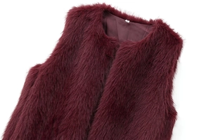 Détail macro du gilet en fausse fourrure bordeaux avec col rond et texture douce