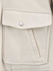 Close-up of beige faux suede jacket pocket with silver snap button and detailed stitching