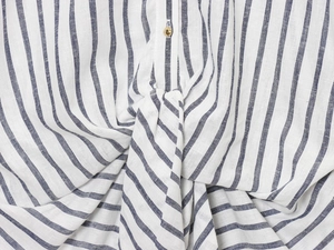 Dettaglio ravvicinato della camicia a righe blu con nodo anteriore e bottone dorato