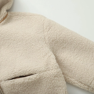Détail de la veste à capuche en polaire sherpa crème avec bordure contrastée brune