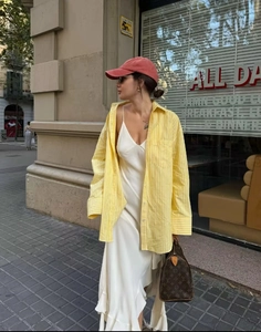 Detail of yellow striped oversized shirt layered over a cream satin slip dress