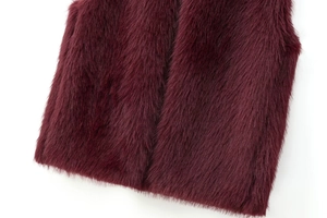 Vue rapprochée du gilet en fausse fourrure bordeaux montrant une texture douce et soyeuse